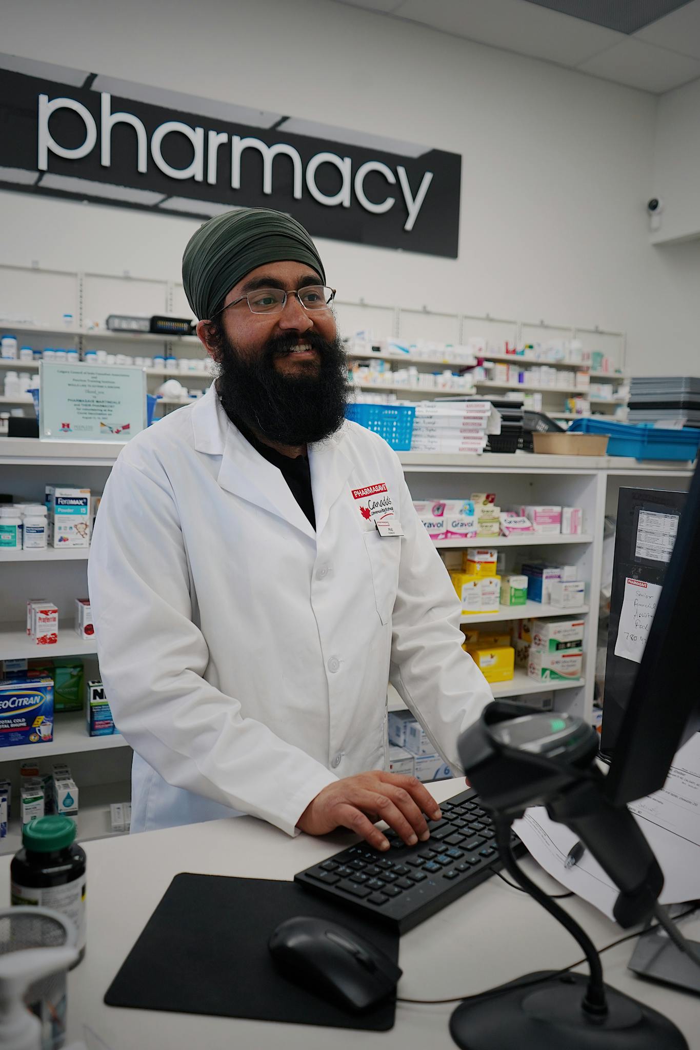 Smiling pharmacist with a turban assisting at the pharmacy counter.